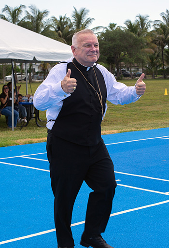 Archbishop Thomas Wenski gives a thumbs-up after making the inaugural basket at the dedication of St. Lawrence School's state-of-the-art basketball-volleyball court, May 16, 2023.