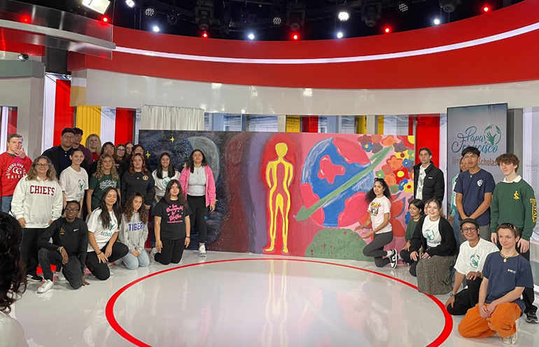 Students from Miami, Los Angeles, New York and Washington, D.C., pose with their mural in Telemundo's Miami studio after taking part in a livestreamed question-and-answer session with Pope Francis as part of the 10th anniversary celebration for Scholas Occurrentes, May 25, 2023. Scholas is an international organization that aims to create a culture of encounter by bringing together young people from different backgrounds to share their problems and collectively seek new solutions.