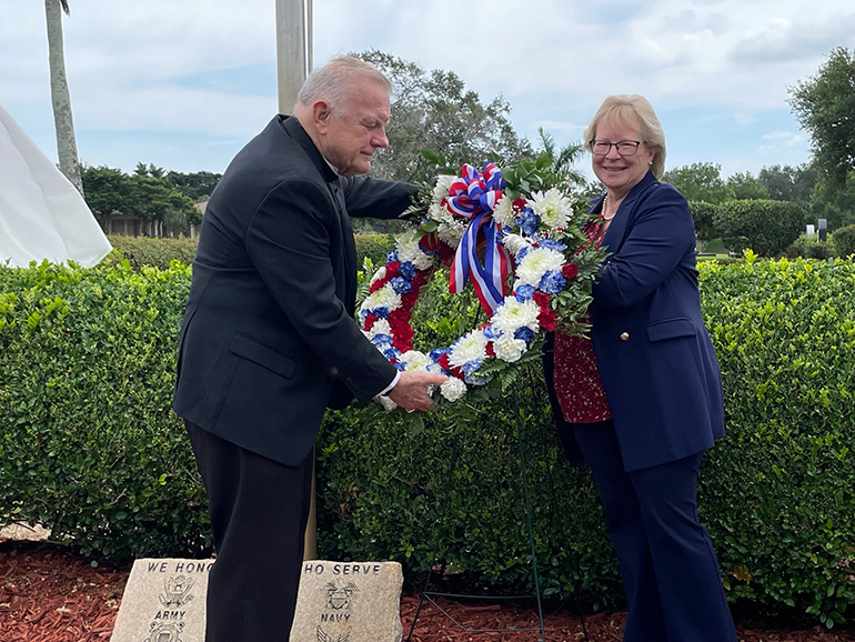 Archbishop Thomas Wenski joins Mary Jo Frick, executive director of Catholic Cemeteries of the Archdiocese of Miami, in placing a wreath in honor of fallen service members after celebrating a Memorial Day Mass at Our Lady Queen of Heaven Cemetery in North Lauderdale, May 29, 2023.