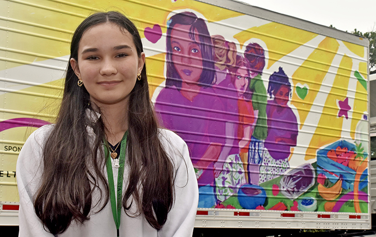 Leila Murray poses with the Feeding South Florida truck that bears the picture she drew for a contest. The art was revealed May 31, 2023, at St. Thomas Aquinas High School, Fort Lauderdale.