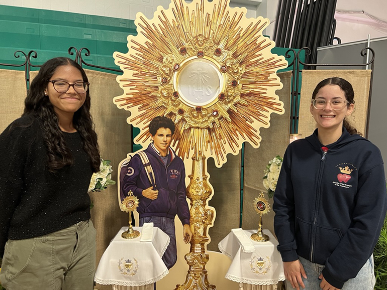 Sarah Zambrano, left, a volunteer, and Samantha Miller, an Apostle of the Pierced Hearts, assisted attendees praying with relics of Blessed Carlo Acutis at the “I Will Always Be With You” Eucharistic Retreat held at St. Brendan High School, June 10, 2023.