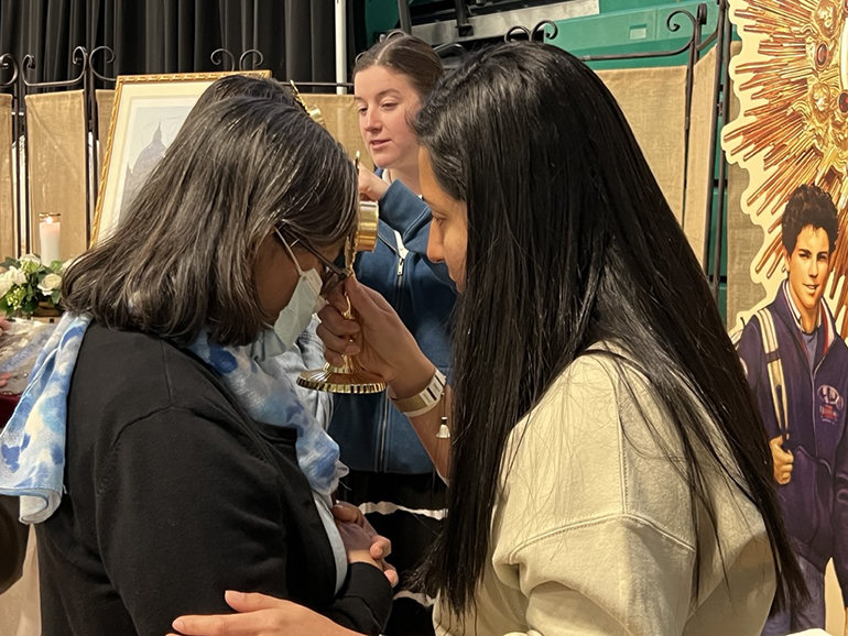 A volunteer presses a relic of Blessed Carlo Acutis to an attendee’s forehead at the “I Will Always Be With You” Eucharistic Retreat held at St. Brendan High School, June 10, 2023.