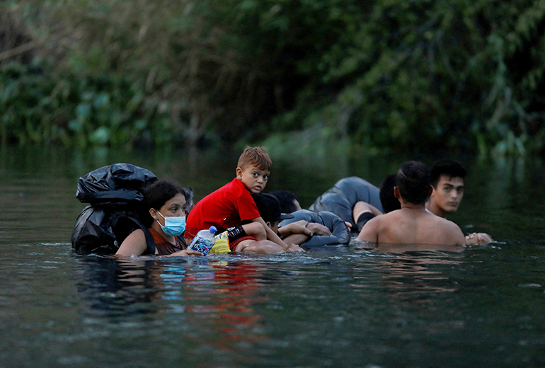 Migrants enter the Rio Bravo River in Matamoros, Mexico May 10, 2023, to cross the border and turn themselves in to U.S. Border Patrol agents before Title 42 ends. (OSV News photo/Daniel Becerril, Reuters)