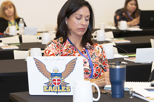 Cristina Rodriguez, principal of St. John Neumann School in Miami, displays her school spirit while taking notes at the all-principals meeting held before the start of the 2023-24 school year, Aug. 4, 2023, at St. Brendan High School.