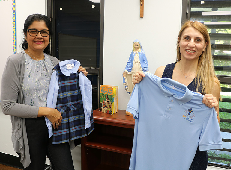Zoraida Perez, St. Malachy religious education director, left, and Pavleta Guenova, preschool director, show off St. Malachy School uniforms with school colors and logos. The Tamarac school is reopening for the 2023-24 school year after closing in 2009.
