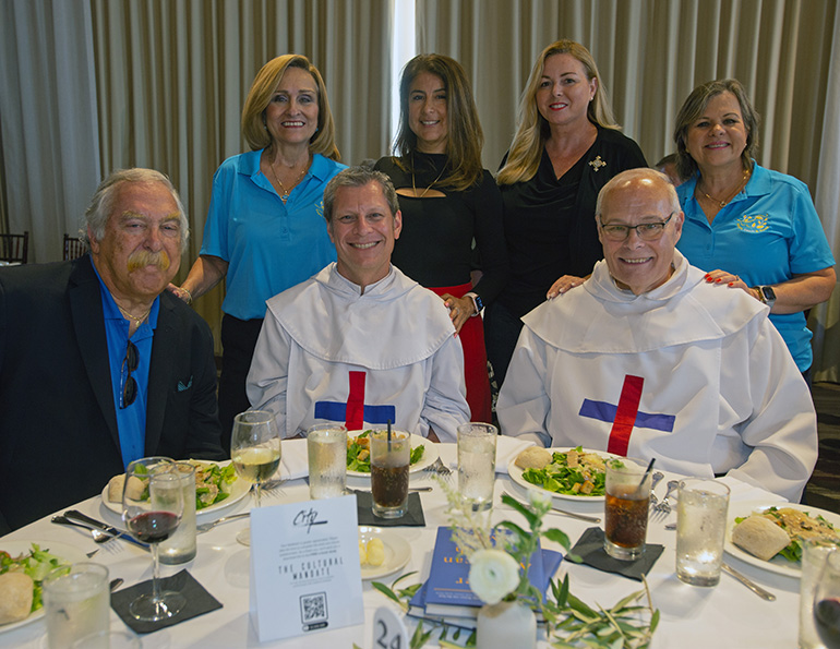 Representatives of Hope, Heart & Home and Our Lady of the Holy Rosary-St. Richard Church pose for a photo after receiving the Distinguished Service Award from Worldviews International, Sept. 7, 2023, in Key Biscayne. From left, seated: Eric Schwindeman, executive director of Hope, Heart & Home; Trinitarian Brother Kevin McGrady and Trinitarian Father Daniel House, pastor of Holy Rosary-St. Richard in Palmetto Bay; standing behind them, Hope, Heart & Home representatives Maria Jacques, of St. John Neumann Parish in Miami, and Carmenza Ortiz, Kathleen Nelson Smith and Rosie Perez Lacayo, all of Holy Rosary-St. Richard.
