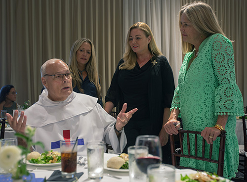 Trinitarian Father Daniel Houde, pastor of Our Lady of the Holy Rosary-St. Richard, converses with Jessica Lancaster, of the National Christian Foundation, Kathleen Nelson Smith, of Holy Rosary-St. Richard, and Chris Lane, of the National Christian Foundation, during the dinner where the Palmetto Bay parish received a Distinguished Service award for its work with the Heart, Hope & Home ministry on behalf of children in foster care, Sept. 7, 2023.
