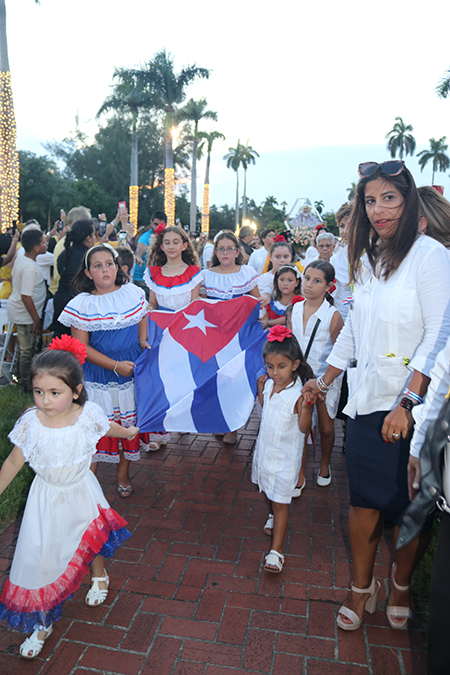 Las hijas y nietas de los integrantes de la Archicofradía de la Virgen de la Caridad de Miami portan la bandera de Cuba, momentos antes de iniciar la Misa de celebración de la Virgen de la Caridad, en su día, el 8 de septiembre, en la Ermita de Miami. Las acompaña a la derecha, Teresa Núñez Pérez, presidenta de la Archicofradía.