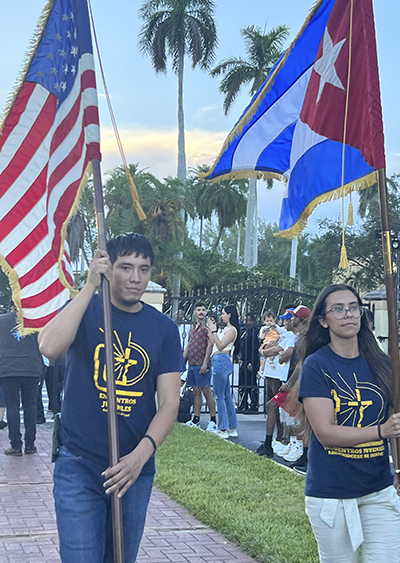 Encuentros Juveniles members Jose Abelino and Brittney Sanchez carry the U.S. and Cuban flags at the start of the celebration of the feast of Our Lady of Charity at her shrine on Biscayne Bay, Sept. 8, 2023.