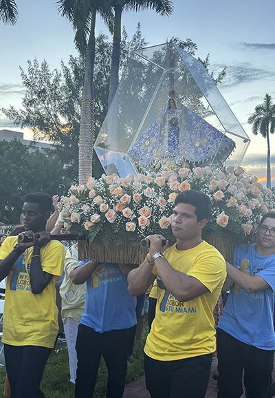 St. Thomas University World Youth Day pilgrims Charles Bwanika, Anibal Palencia, and Arturo Zayas process with the statue of Our Lady of Charity during the celebration of her feast dat at her shrine on Biscayne Bay, Sept. 8, 2023.