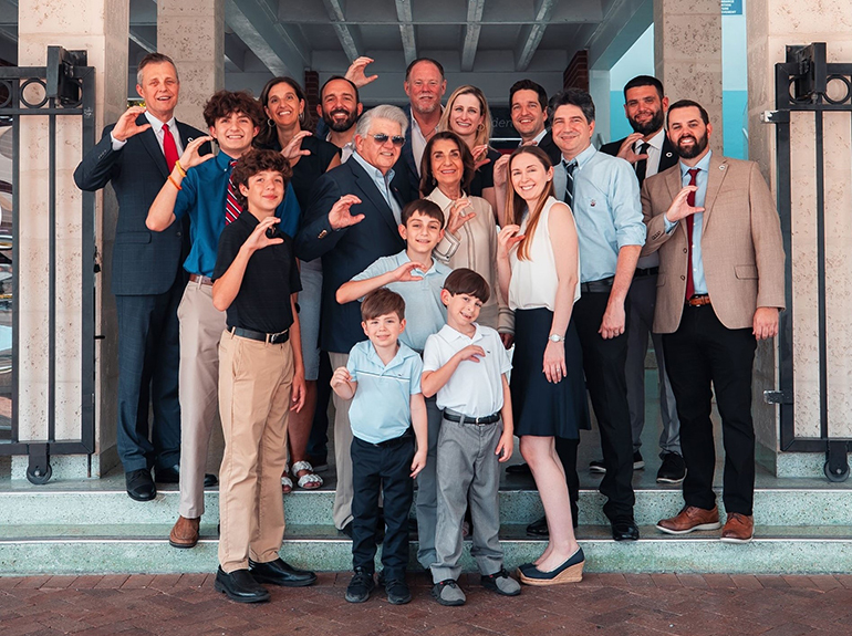 The Alvarez family pictured in front of Christopher Columbus High School’s main entrance, which will be renovated along with the ‘A’ Building with the family’s transformational donation, Sept. 13, 2023. From left, top row: Columbus President Thomas Kruczek, Sandy Reus, James Reus ’96, Hector Garcia ’84, Krystle Alvarez, Eduardo Alvarez ’04, Albert Tamayo ’03, Columbus vice president of Finance; second row: Sam Reus ’24, Maximo Alvarez, Esther Alvarez, Max R. Alvarez ’98, Nicholas Ramos ’04, Columbus vice president of Advancement; bottom row: Eric Reus ’28, Gabriel Alvarez, Max J. Alvarez ’29, Lucas Alvarez and Leilani Alvarez.