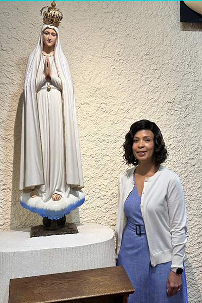 Thais Garcia, posing in front of a statue of Mary at her parish, Our Lady of the Lakes in Miami Lakes, says she has no doubt that the image that she gazes at in the Eucharist, in the form of bread, is Jesus’ body.
