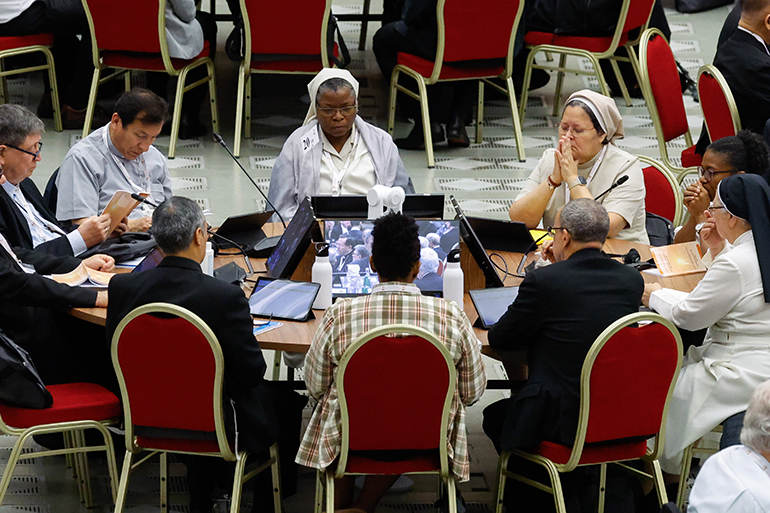 Members of the assembly of the Synod of Bishops pray before a working session of the assembly of the Synod of Bishops in the Vatican's Paul VI Audience Hall Oct. 17, 2023. (CNS photo/Lola Gomez)