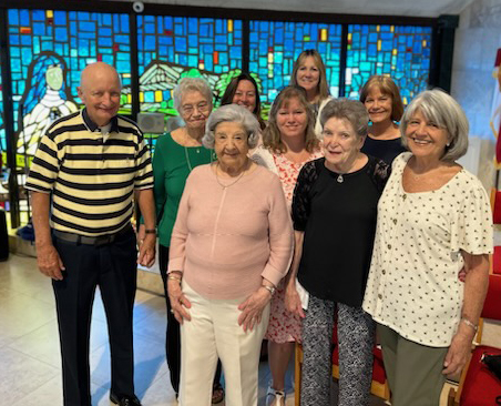 While celebrating her 100th birthday July 16, 2023, Muriel Conroy, center front, poses by the stained glass window she helped design in her longtime parish, St. Pius X in Fort Lauderdale, with family members, from left: Mickey and Jeanne Marshall (niece and her husband); Patty Rucki, Tara Bonelli and Sharon Petty (great nieces); and Maureen Rankin, Patricia Kerr and Kathy Wilson (nieces).