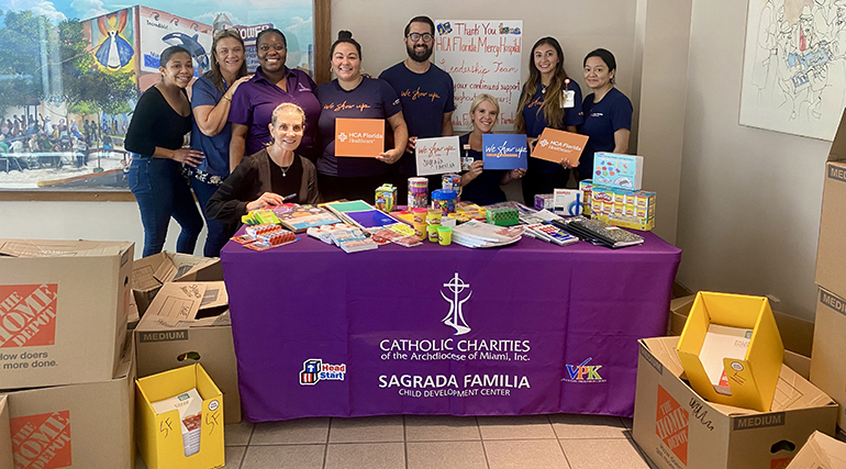 HCA Florida Mercy Hospital staff pose with some of the school supplies they collected and delivered to Catholic Charities Sagrada Familia Child Development Center in Miami for the 2023-24 school year.