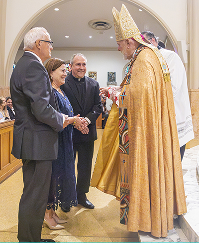 Carl Lowell and Ely Fleites from Epiphany Church receive the Jubilaeum Cross from Archbishop Thomas Wenski during the Archdiocese of Miami's 65th anniversary vespers service, Oct. 22, 2023, at St. Mary Cathedral. They were accompanied by their pastor, Father Jose Alvarez.