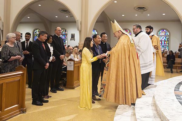 Chien Pham and Thanh Thuy Truong from Our Lady of La Vang Vietnamese Mission receive the Jubilaeum Cross from Archbishop Thomas Wenski during the Archdiocese of Miami's 65th anniversary vespers service, Oct. 22, 2023, at St. Mary Cathedral. They were accompanied by their pastor, Father Joseph Long Nguyen.