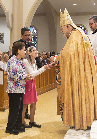 Helen Albertson and Eva Soche from St. Agnes in Key Biscayne receive the Jubilaeum Cross from Archbishop Thomas Wenski during the Archdiocese of Miami's 65th anniversary vespers service, Oct. 22, 2023, at St. Mary Cathedral. They were accompanied by their pastor, Father Juan Carlos Paguaga.