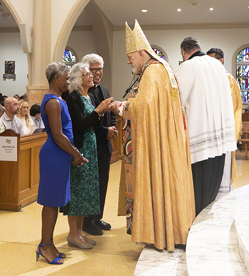 Lisa Ford and Rosalinda Hally, from St. Peter in Big Pine Key, receive the Jubilaeum Cross from Archbishop Thomas Wenski during the Archdiocese of Miami's 65th anniversary vespers service, Oct. 22, 2023, at St. Mary Cathedral. They were accompanied by their pastor, Father Jesus "Jets" Medina.