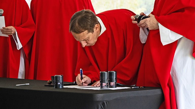 Father Len Plazewski signs documents affirming he carried out his responsibilities "true and correct" as vice-postulator of the canonization cause of Antonio Inija and the 57 companions.