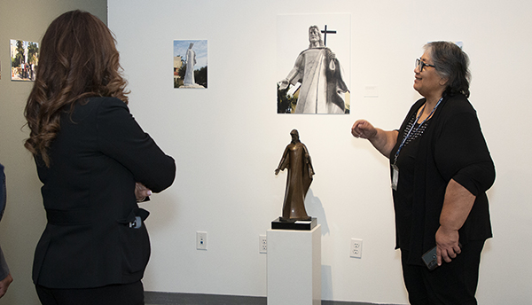 Museum coordinator Isabel Medina, right, speaks to guests at the opening of Roberto Perez Crespo's "The Hands of Christ" exhibit at St. Thomas University, Oct. 26, 2023. At rear is a scale model of the Christ he sculpted for St. Martha Church in Miami Shores.