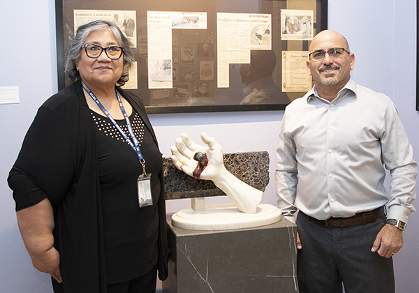 Roberto Perez Crespo poses with Isabel Medina, St. Thomas University's museum coordinator, assistant archivist and art gallery director St. Thomas University archivist and opening of "The Hands of Christ" exhibit at St. Thomas University, Oct. 26, 2023. Between them is the first piece he created in the U.S., "Perdón, Señor" (Forgive me, Lord).