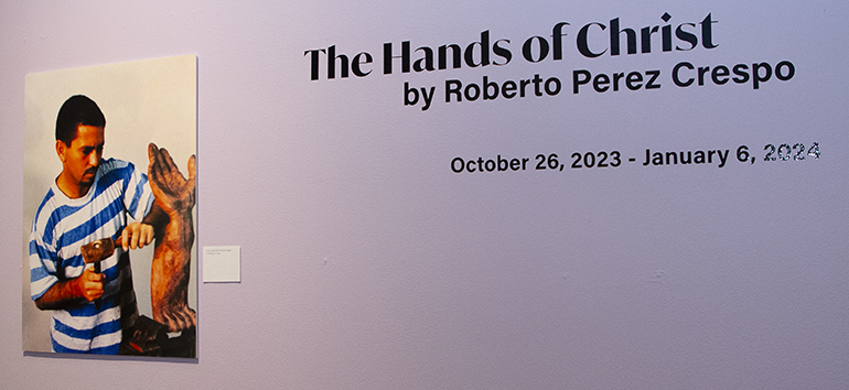 A young Roberto Perez Crespo is shown at work at the entrance to "The Hands of Christ" exhibit at St. Thomas University, Oct. 26, 2023.