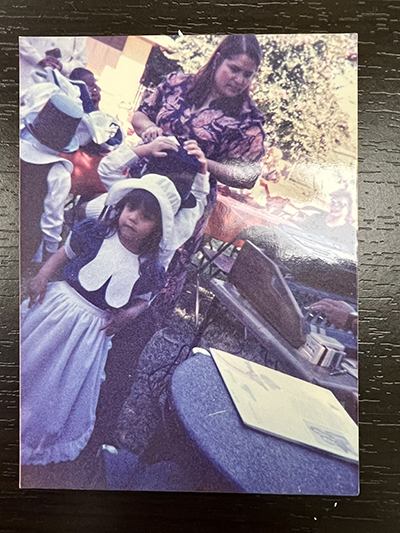 Alejandra Presiga treasures many photographs, including this one, from her education at Good Shepherd Child Care Center in the early 1990’s. In this photograph, Alejandra (front) is dressed in a pilgrim costume that her mother, Oliva Presiga, handmade for a Thanksgiving show.