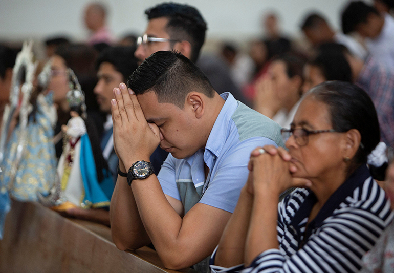 Worshippers pray before a procession on the perimeter of the Metropolitan Cathedral in Managua, Nicaragua, Nov. 26, 2023, as the Nicaragua government banned street processions this year due to unspecified security concerns.