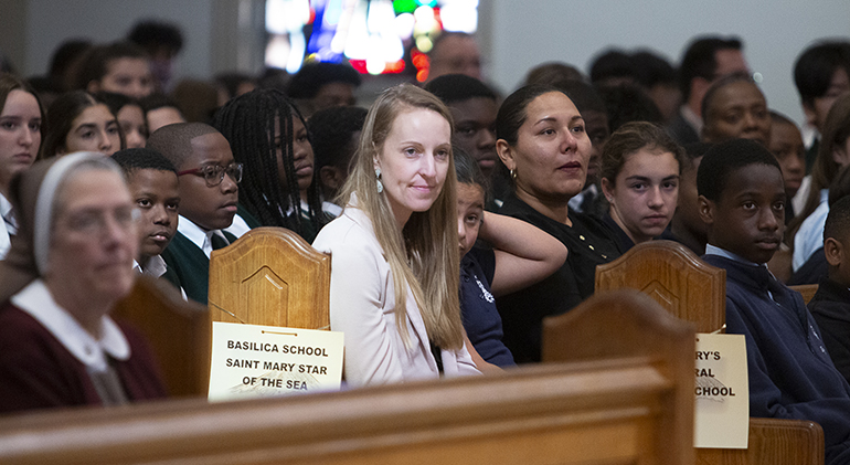 Joanna Morris, principal of the Basilica School of St. Mary Star of the Sea, sits alongside her students at the All Schools Mass, Jan. 31, 2024, at St. Mary Cathedral. They set out from Key West at 4:30 a.m. to attend the Mass. Representatives of all 64 archdiocesan elementary and high schools gathered for the second annual  Mass to mark Catholic Schools Week, Jan. 28-Feb. 3.