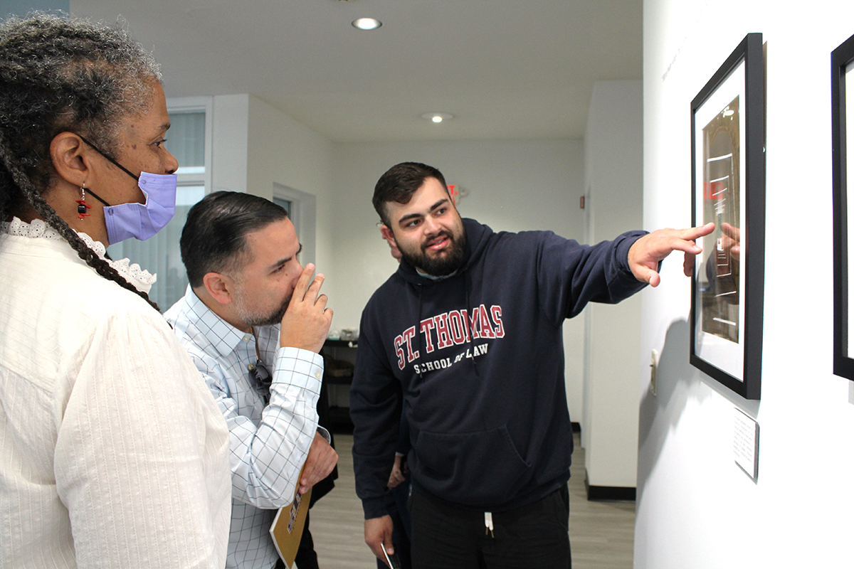 Jacob Covas, a law student at St. Thomas University, points to details of a photo taken at the Holocaust Memorial in Miami Beach. The photo is part of the 'Visions of Faith' interfaith sacred art exhibit at St. Thomas University's Rev. Jorge A. Sardiñas Gallery, which was unveiled on March 12, 2024.