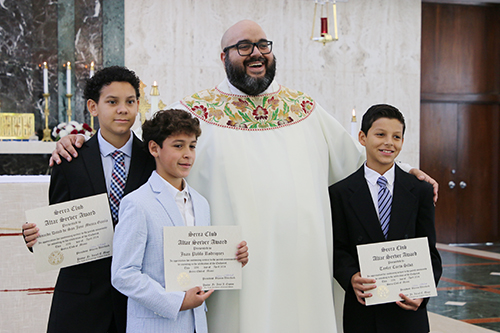 Altar servers Leonardo Mujica, of Our Lady of Guadalupe Church, in Doral; Juan Pablo Rodriguez, of Our Lady of Charity National Shrine, in Miami; and Tayler Cueto Silva (right), of Our Lady of Guadalupe Church receive their recognition from Father Matthew Gomez, archdiocesan vocations director at the Altar Server Awards ceremony on Saturday, April 20, 2024. This event was organized by the Serra Clubs of Miami and Broward, at St. John Vianney College Seminary.