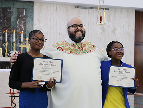 Altar servers Methushella Cape (left) and Carly Sylvain, of St. Bartholomew Church, in Miramar receive their recognition from Father Matthew Gomez, archdiocesan vocations director at the Altar Server Awards ceremony on Saturday, April 20, 2024. This event was organized by the Serra Clubs of Miami and Broward, at St. John Vianney College Seminary. Cape and Sylvain were two of the approximately 130 altar servers who received awards for their service.