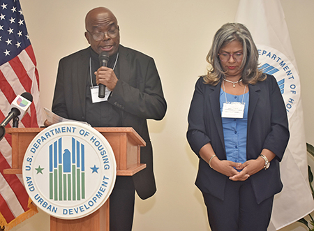 Father Samuel Muodiaju, pastor of St. Monica Church, leads prayer as Juana D. Mejia of Catholic Housing Management bows her head. They prayed April 30 during a $ 6.72 million check presentation for the St. Monica Gardens home from the U.S. Department of Housing and Urban Development.