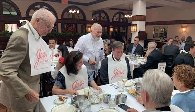 Archbishop Thomas Wenski (center) greets guests at Cheers for Charity at Joe's Stone Crab on Miami Beach on April 23, 2024. Celebrating its 13th anniversary, the annual gathering raises funds for archdiocesan charities.