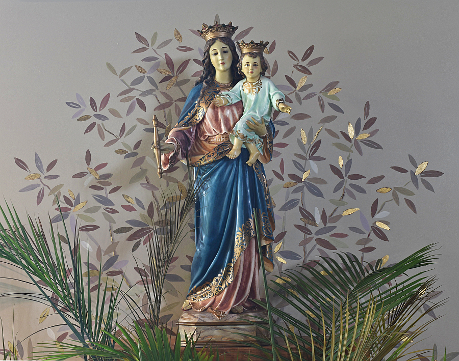 Green, gold and brown leaves, and even live palm fronds, surround a statuette of the patron saint on the chancel at Mary Help of Christians Church in Parkland.