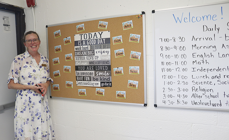 Brenda Blanton, a teacher at the new De La Salle Little School, poses with the students' school schedule Aug. 18 after the school was blessed by Archbishop Thomas Wenski.