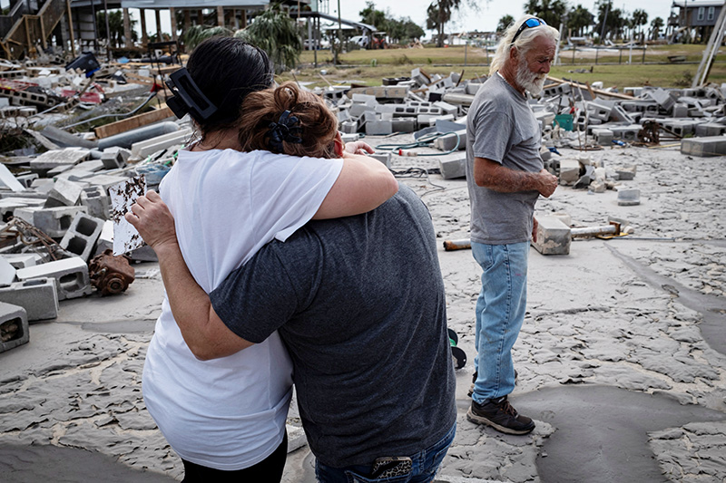 Women embrace Sept. 28, 2024, as Dave (no last name provided) looks at the remains of his destroyed house in Horseshoe Beach, Florida, following Hurricane Helene.