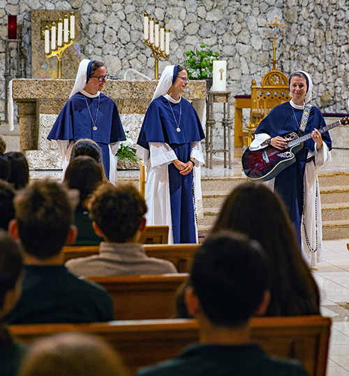 Sister Ann Immaculee plays the guitar and sings as Sister Lumen Gloriae (far left), and Sister Catherine Joy Marie look on. The three sisters are part of the Sisters of Life, a religious order from New York, who visited St. David School in Davie Sept. 26, 2024, to speak to the students about pro-life issues.