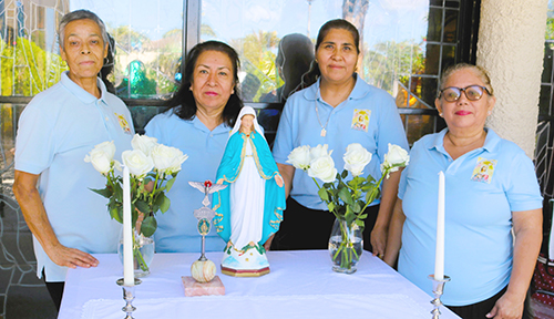 Laura Santos (izquierda) ayuda a los miembros de la Legión de María de la iglesia Our Lady Queen of Heaven a preparar una mesa para la inscripción de nuevos miembros, después de la Misa del 3 de noviembre. Durante el año del aniversario, la parroquia se enfoca en el crecimiento de los ministerios. "Estamos trabajando juntos para ayudar a las personas a fortalecer su fe", dijo.