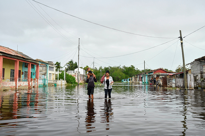 Una familia camina por una calle inundada un día después de que el huracán Rafael tocara tierra en Batabano, Cuba, el 7 de noviembre de 2024. El pueblo cubano está sufriendo inmensas dificultades después de desastres naturales consecutivos en las últimas semanas, el colapso del sistema eléctrico y la escasez de la comida.