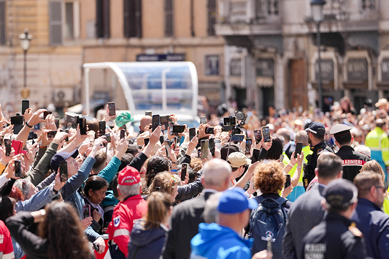 People raise their phones to capture the arrival of the casket of Pope Francis, transported in a popemobile to the Basilica of St. Mary Major in Rome April 26, 2025, following his funeral Mass at the Vatican.