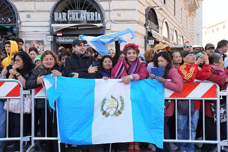 People stand behind the flag of Argentina outside the Basilica of St. Mary Major in Rome April 26, 2025, where the body of Pope Francis will arrive following his funeral Mass at the Vatican. The pope chose the Marian basilica as his burial place.