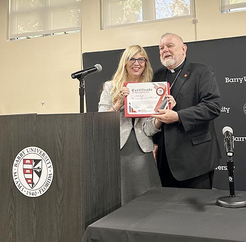 Archbishop Thomas Wenski receives a certificate at the Barry University Institute for Immigration Studies 2nd Annual Conference April 9-10 in Miami Shores from event organizer Giselle Rios, professor of music and the institute's founding director.