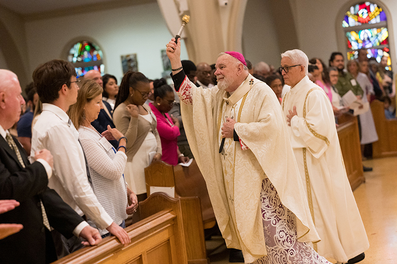Archbishop Thomas Wenski sprinkles holy water on the candidates, their sponsors, family and friends during the annual Rite of Reception at St. Mary Cathedral May 4, 2025.