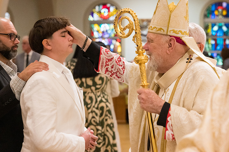 Archbishop Thomas Wenski anoints the forehead of a candidate during the annual Rite of Reception at St. Mary's Cathedral in Miami May 4, 2025.