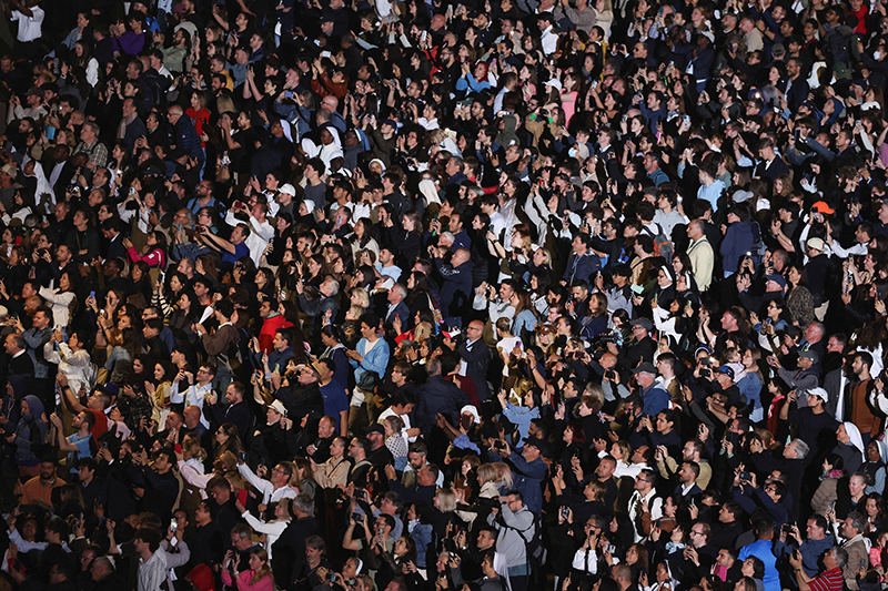 People take cellphone photos as black smoke billows from the chimney on the Sistine Chapel May 7, 2025, on the first day of the conclave. The black smoke indicated that cardinals did not elect a new Pope.