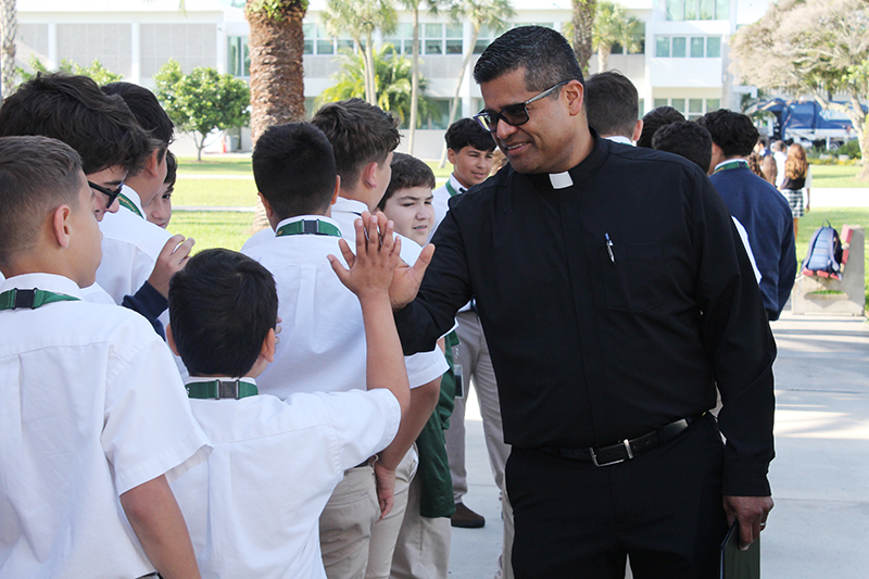 Father Milton Martinez Blass, archdiocesan director of the Office of Vocations, greets sixth grade students from Catholic schools with a "high five" as they arrive for the Focus 11 Vocations Rally at St. John Vianney College Seminary in Miami on May 15, 2025.