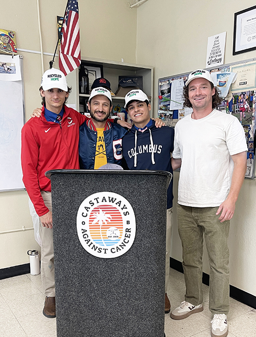 Representatives from Christopher Columbus High School’s Environmental Club celebrate creating Recycled Hope baseball caps, made from recycled water bottles, for Castaways Against Cancer Nov. 20, 2024. Pictured from left are Julian Aviles from Columbus; Eric Pino from Castaways Against Cancer; Joshua Fernandez from Columbus; and Nick Burman from Campus for GREEN, the company that created the caps.