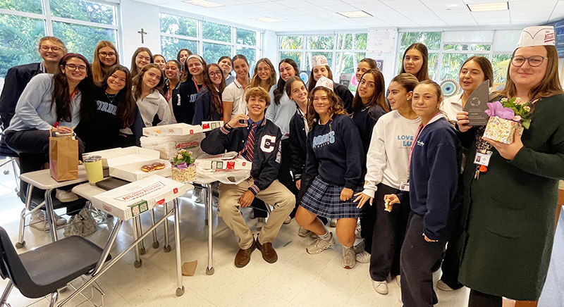 Joshua Allen (seated center) represents Christopher Columbus High School at Our Lady of Lourdes Academy’s celebration May 2025 for the girl’s school’s victory in the “Battle of the Bins” recycling competition.